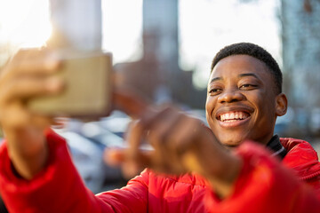 Young man smiles while video chatting with friend on smartphone outdoors
