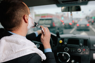 Businessman shaving in car by razor and foam at the wheel. Shaving man in the driver's seat....