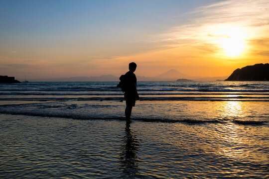 シルエットの男性と逗子海岸の夕日