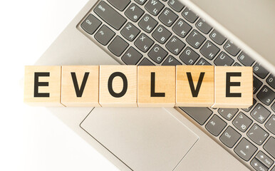 Word evolve. Wooden cubes with letters isolated on a laptop keyboard. Business Concept image.