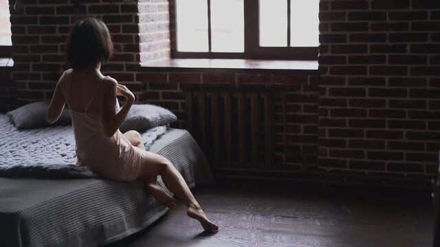 Elegant beautiful female seductive model in nude underwear relaxing on bed and flirting. Sensual Asian woman in sexy lingerie posing in bedroom for camera. Glamour erotic content.