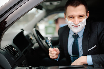 Businessman shaving in car by razor and foam at the wheel. Shaving man in the driver's seat....