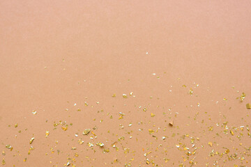 Shiny golden confetti on beige background. Top view, copy space