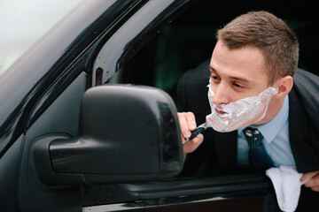 Businessman shaving in car by razor and foam at the wheel. Shaving man in the driver's seat....