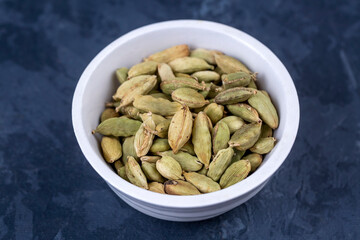 Closeup top view of dried green Elettaria cardamomum fruits with seeds, cardamom spice scattered