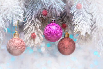 Christmas balls on frosty fir-tree branches over holiday defocused lights