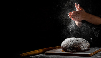 woman chef hand clap with splash of white flour and black background with copy space. woman's hands Making bread