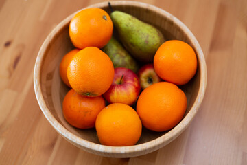 Wooden bowl with fresh fruits, oranges, apples and peaches, on wooden table, vegetarian meal, new trends, healthy food, nutrition, diet
