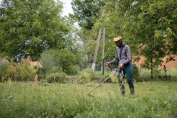 Man mowing the lawn in his garden. Gardener cutting the grass. Lifestyle.