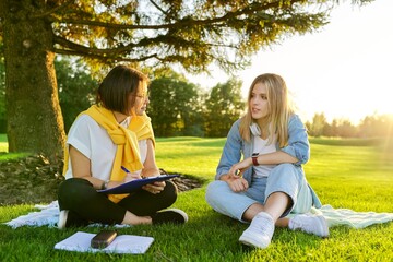 Female teacher psychologist social worker talking to teenage student on the lawn