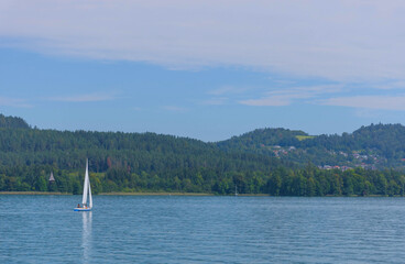 Boating and sailing on the clear waters of alpine Lake Worthersee, famous tourist attraction for many water activity, in Carinthia region, Austria