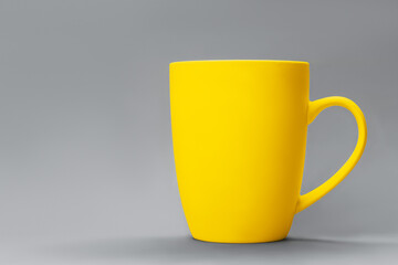 Demonstrating trendy colors 2021 - Gray and Yellow. Yellow cup of cofee against grey background. Minimal concept. Copy space, muck up, front view.