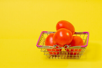 three tomatoes in a supermarket basket on a yellow background