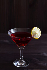 cosmopolitan cocktail. Martini glass with cocktail and olives on black background. Red cocktail with lime on the wooden table. copy space. alcohol drinks. vertical.