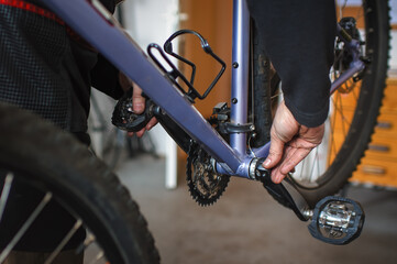 Hands of a mechanic holding a bicycle crank to check the clearance in the bottom bracket on a...
