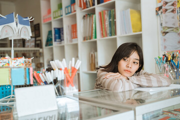 Portrait boring young girl entrepreneur waiting customer working in a stationery shop.