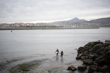 una pareja de sufistas entrando al agua en mar en calma. 