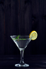 Martini glass with cocktail and ice on black background. Cocktail Margarita with lime and green mint on the wooden table. copy space. alcohol drinks. vertical