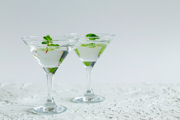 alcohol drinks. Two Martini glasses with cocktail and ice on white background. Cocktail Margarita with lime and green mint on the table. copy space.