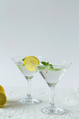 alcohol drinks. Two martini glasses with cocktail on white background. Cocktail Margarita with lime and mint on the table. copy space. vertical