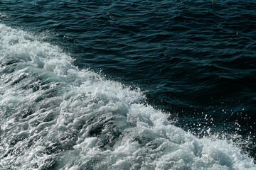 Splashing sea water with foam, bubbles and defocused lights. Close up detail of the wake of large cruise ship 