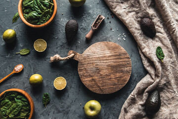 Healthy foods, cooking and vegetarian concept spinach leaves, lemon, apples, avocado, cutting board