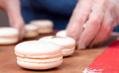 Macaroons close-up, in a blurry background, a hand that corrects the dessert.