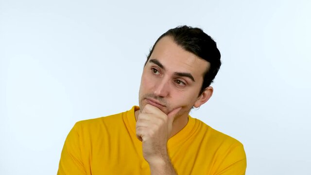 Thoughtful expression of a  man with hand under chin. Puzzled casual guy, thinking emotion, looking to camera.