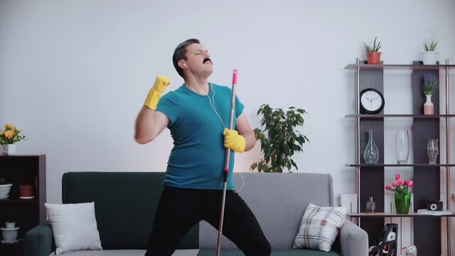 The cleaning man sings a song like a rock star.Sings the song comically.