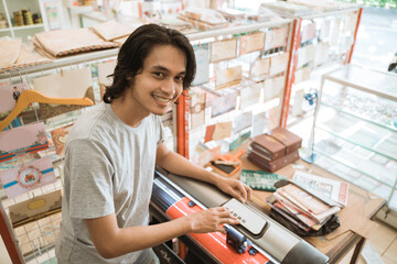 Fototapeta na wymiar Young male entrepreneur Making sticker paper by machine working in a stationery shop.