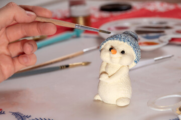 Chocolate snowman figurine is painted with a brush. Selective focus.