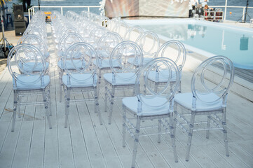 Glass chairs stand in a row in a beautiful wedding outing ceremony