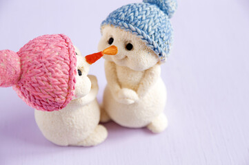 Christmas chocolate figurines of snowmen touching their noses. On a wooden background. Selective focus.