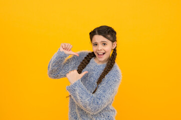 look over there. beauty and fashion. hairdresser salon for child. happy childhood. wearing casual knitted clothes. amazed teenage girl. pretty kid with braided brunette hair. pointing thumb up finger