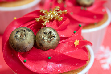 Golden blueberries with a snowflake on cupcakes with red cream. Selective focus.