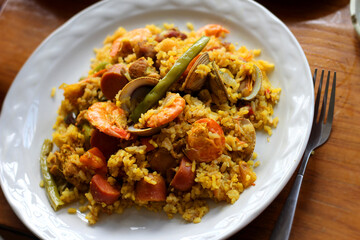 White  dish with rice, shrimp, chili, clams and a fork