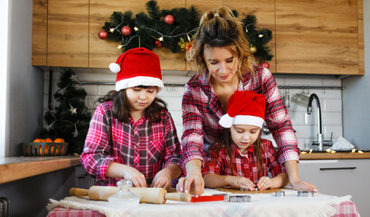 Mom and daughters learn how to make cookies in the kitchen decorated for Christmas