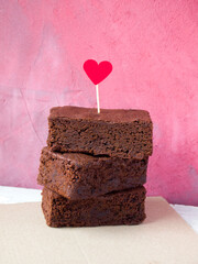 Slices of delicious brownies are stacked on top of each other. The top piece of chocolate cake is...