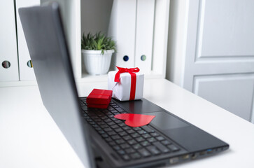 gifts in bright wrapping paper are on a work laptop. Buying gifts. Working hours, work at home.