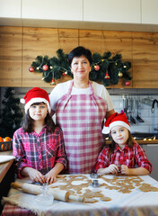 grandma and two granddaughters cook cookies in the kitchen.