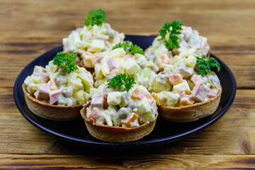 Traditional Russian festive salad Olivier in tartlets on wooden table