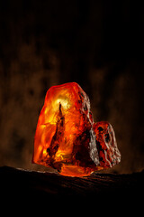 Beauty of natural raw amber. A piece of yellow-red transparent natural amber on piece of stoned wood