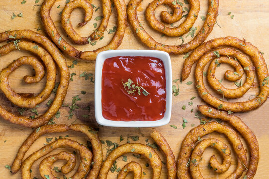Overview of spiral form fried potatoes with a cup of ketchup sauce