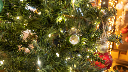 Defocused green ball is on fir Christmas tree. Close-up image of green New Year toy decoration on yellow background. Happy New Year concept.