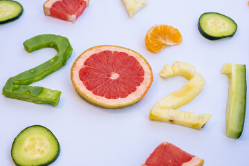 Exquisite fruits cut in the shape of the new year 2021 on a white table.