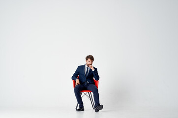 an elegant gentleman in a suit sits on a red chair in the middle of the room