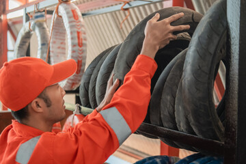 mechanic in a wearpack uniform picks up a tire from the rack at a motorbike spare part workshop