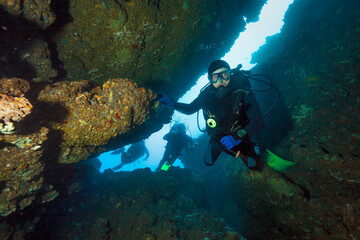 Scuba Divers explore underwater cave.
