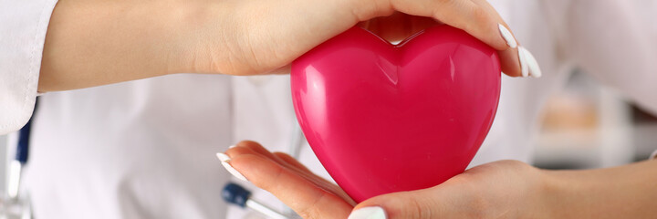Close up of woman cardiologist in white lab coat demonstrating symbol of love and healthy cardiovascular system