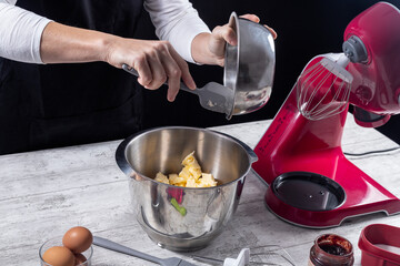 Pastry chef working putting butter in boll of kneading machine to make dessert. Concept of cooking and pastry at home. Selective focus